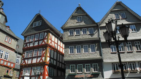 Auf dem Bild sieht man die Giebel von drei Häusern. Zwei Häuser sind mit Schiefer gedeckt. Bei dem linken Haus ist das Fachwerk zu erkennen. Rechts im Vordergrund steht eine alte Straßenlaterne. 