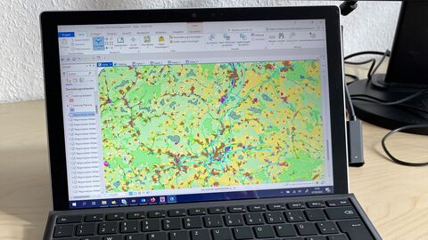 Auf dem Bild sieht man ein Tablet mit Tastatur. Der Bildschirm zeigt eine Anwendung, bei der eine bunte Karte visualisiert ist.