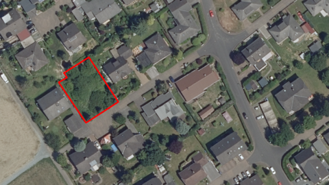 Orthophoto mit Baulücke Das Bild zeigt ein Dorf von oben. Man sieht viele Häuser und Strassen. Eine Baulücke ist rot eingezeichnet.