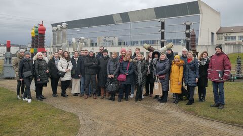 Personengruppe vor rechteckig grauem Gebäude