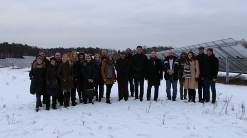 Personengruppe im Schnee, im Hintergrund grauer Himmel hinter hügeliger Landschaft
