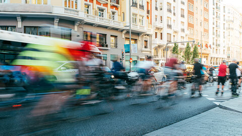 Radverkehr vor mehrgeschossiger Häuserreihe Radverkehr in Bewegung vor mehrgeschossiger Häuserreihe in bunten Farben
