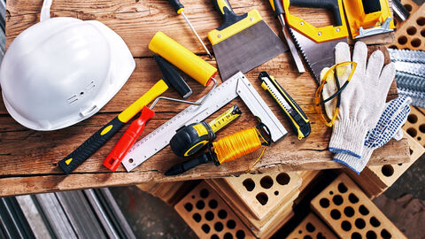 Werkzeuge für den Bau Werkzeuge für den Bau auf Holzbrett und braune Ziegelsteine