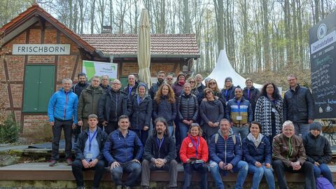 Gruppe von Menschen vor Hütte im Wald