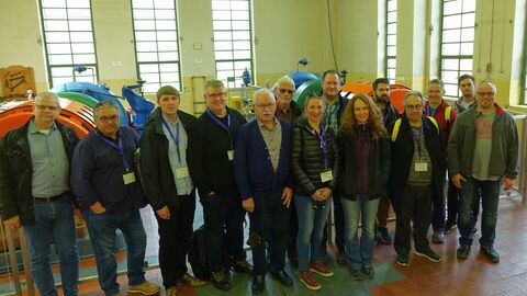 Menschen im Gebäude vor grüngelber Wand mit Fenstern